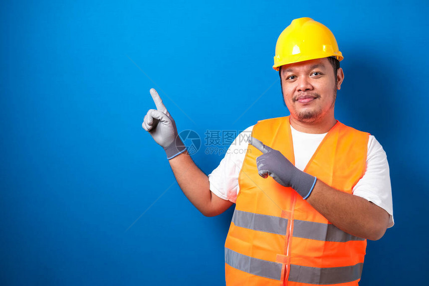 身戴头盔的亚洲胖工人在面对侧时手握着东西图片