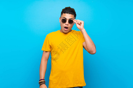 年轻男子穿着黄色衬衫与孤立的蓝底图片