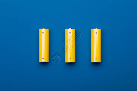 三个黄色AA碱电池Mignons或蓝色背景的NiMH可充电图片