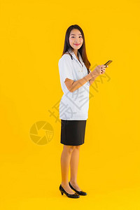 女以黄色孤立背景使用智能手机的年轻女医生图片