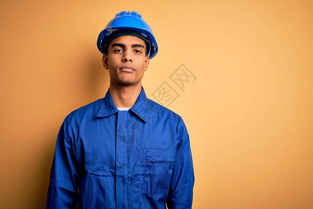 身着蓝制服和头盔的年轻英俊的非裔美国工人在脸上露出严肃的表情图片