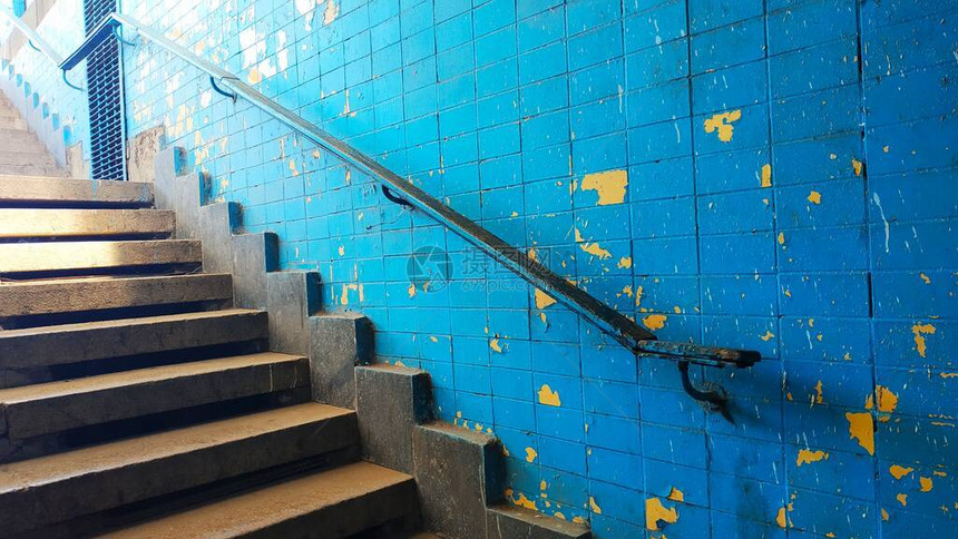 旧出口从楼梯的地下通道上出来在蓝色破墙背景图片