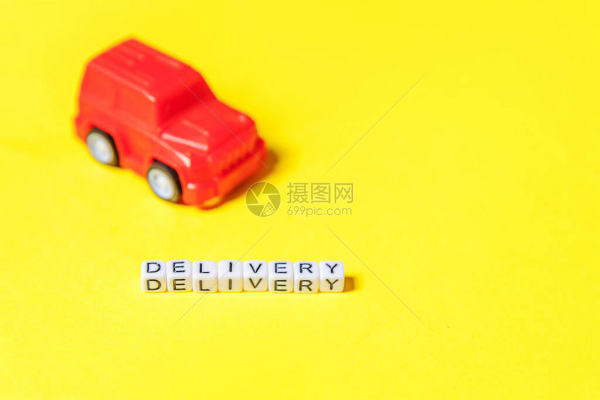 只需设计红色玩具车和在黄色彩背景上隔离的题词DELIVERY字网上购物网上购买电子商务包裹送货服务概图片