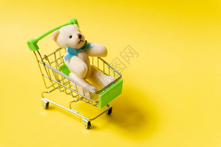 黄色背景的泰迪熊购物车儿童节的概念图片