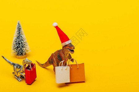 圣塔帽中的玩具恐龙有购物袋和图片