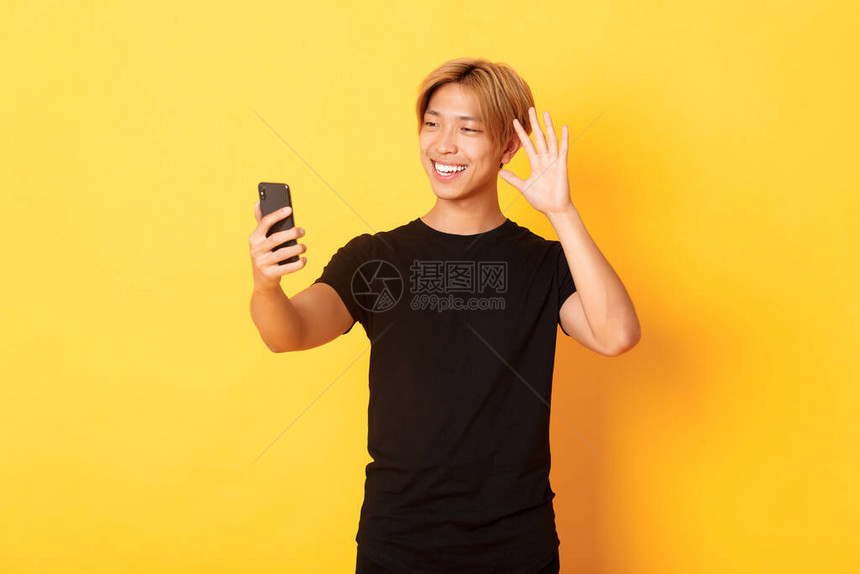 友好英俊的亚洲男子的肖像对智能手机相微笑和挥手用视频电话向朋友问好图片