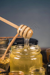 蜂蜜流入玻璃罐的木制北斗各种类型的蜂蜜蜂花粉蜂胶和木制蜂背景图片