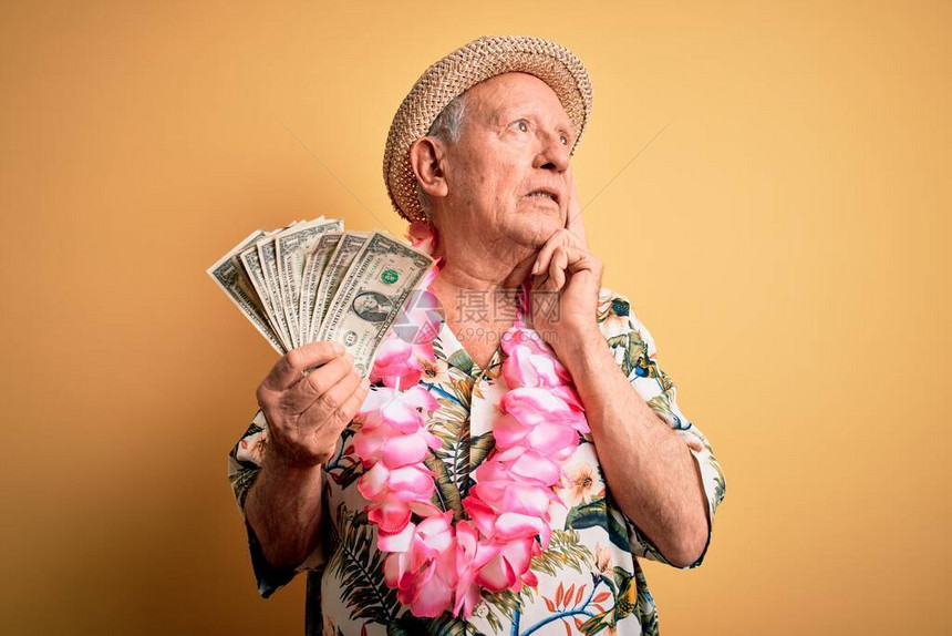 穿着暑假帽子的灰色头发长老人拿着一副严肃的美元面孔想着问题图片