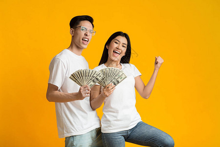 年轻快乐的富有的亚洲夫妇在黄色工作室背景上图片