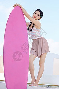 室外抱着冲浪板的美女背景图片