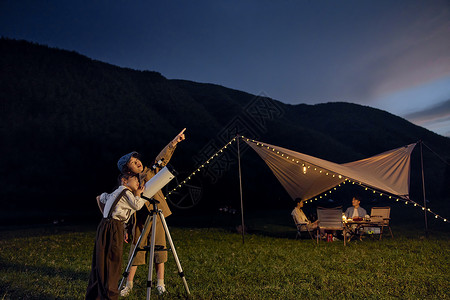 看星星的孩子儿童露营夜晚使用天文望远镜看星空背景
