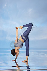 蓝色天空背景做瑜伽锻炼的女性图片