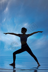 蓝色背景下做瑜伽的女性剪影高清图片
