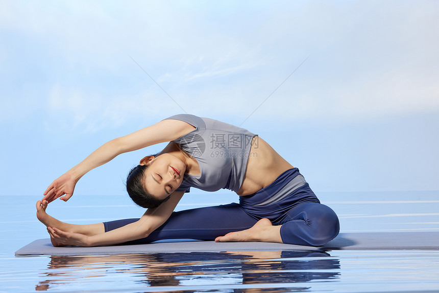青年女性做瑜伽水面倒影图片