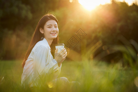 绿色长裙美女户外享受秋日阳光背景