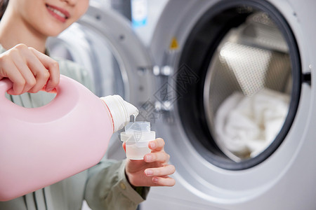 洗涤标示给衣服添加洗衣液的女性特写背景