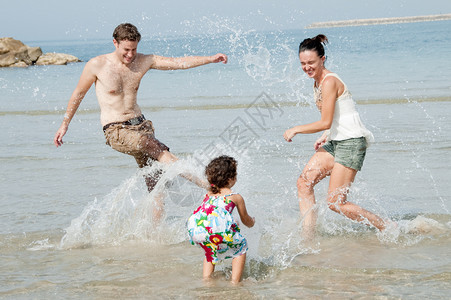 父亲母和女儿在沙滩上玩耍图片