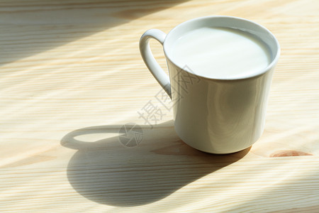 一杯牛奶与站在木制背景上的影子图片