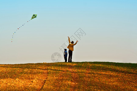 母亲和儿子在秋天放风筝图片
