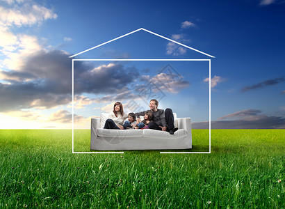 坐在绿草地上沙发上的微笑的家庭被房子形式包围着图片