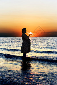 在波罗的海日落背景的怀孕妇图片