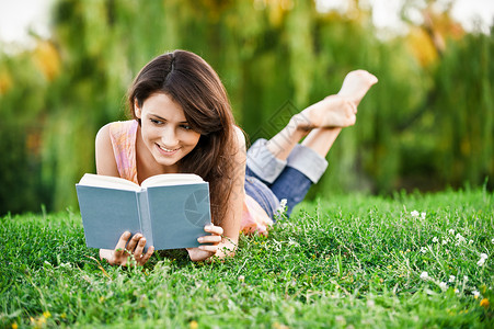 女学生躺在草坪上看课本图片