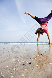 年轻女孩在沙滩上表演杂技图片