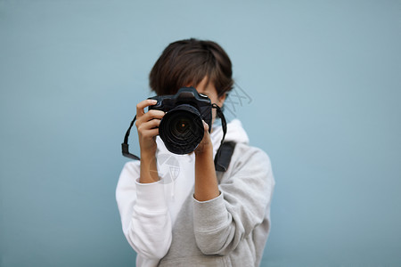 拥有专业相机的年轻妇女有选择地关注镜背景图片