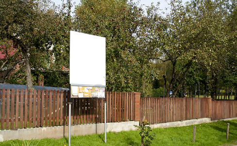 纯粹的布告板靠近栅栏在篱笆后背景图片