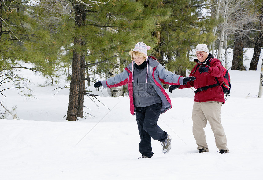 活跃的退休夫妇在雪地里玩耍图片