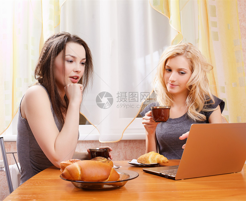 两个女孩的肖像手持笔记本电脑喝茶机鸡图片