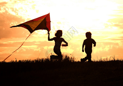 两个孩子在日落时放风筝图片