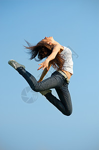 体操跳跃的美丽的妇女反对蓝天图片