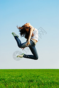 体操跳跃的年轻女子反对蓝天图片