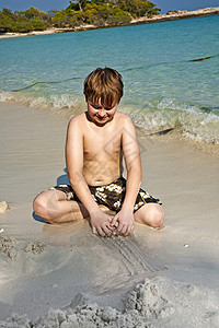 男孩在美丽的海滩玩耍沙图片