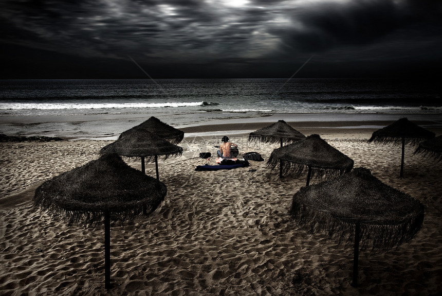 在沙滩上夜幕一个男人坐在沙图片