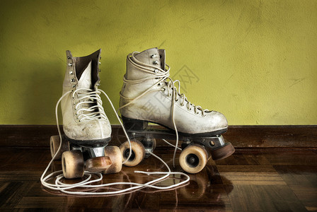 黄墙背景上带大鞋带的旧溜冰鞋背景图片