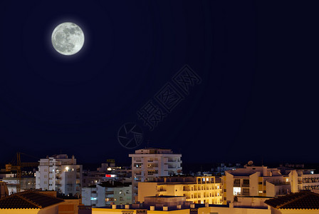 天空中满月的夜间城市景观图片