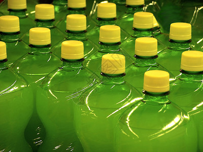 超市里排列着黄色瓶盖的绿色瓶子图片