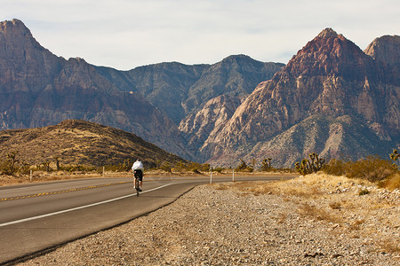 一个骑自行车的独行车手兜售着一条通往远山的图片