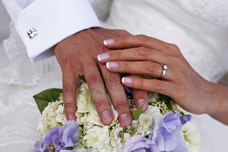 新郎和新娘的手与婚礼花束图片
