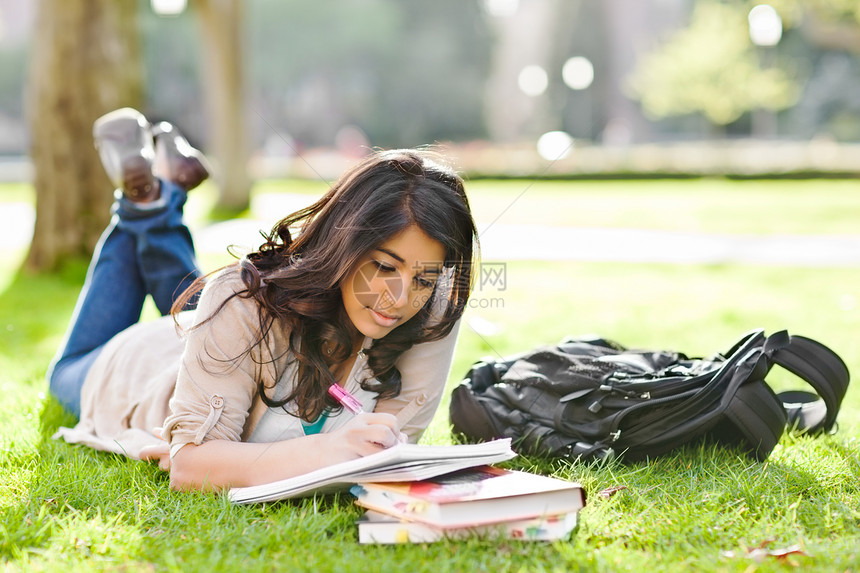 一名亚裔学生在校园草坪上学图片
