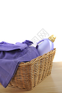 一个洗涤剂瓶子和紫色的洗衣放在木制桌图片