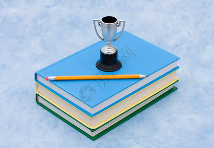 一堆书有奖杯和蓝背景的铅笔背景图片