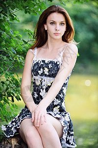 在夏日绿色公园坐在湖边对面的树桩上身着黑裙子的年轻有吸引图片