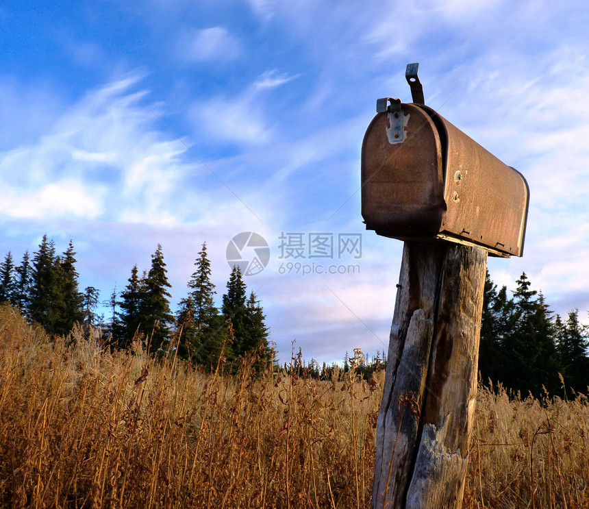 一个生锈的古老农村信箱挂在干草的木桩上图片