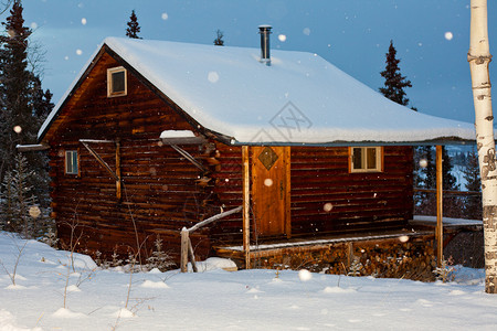 雪花掉在舒适的冬季小屋上邀请图片