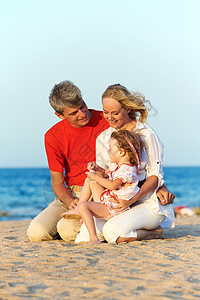 日落时在红海滩玩耍的幸福家庭图片
