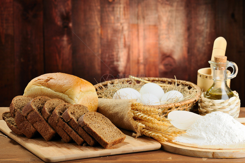 木桌上的切片面包和小麦图片