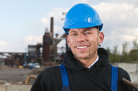 穿着蓝色硬帽的微笑工人站在工业图片